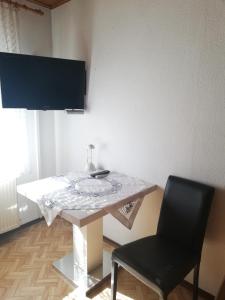 a table with a chair and a television on a wall at Weingut und Gästehaus Vongerichten in Oberhausen