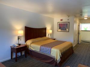 1 dormitorio con 1 cama y 1 mesa con 2 lámparas en Airport Inn, en South San Francisco
