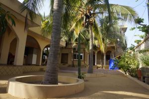 a courtyard with palm trees in front of a building at Ramaya Auberge Espagnole in Grand-Popo