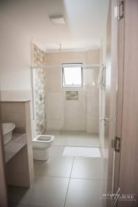 a white bathroom with a toilet and a sink at Hotel De Klomp in Carambeí