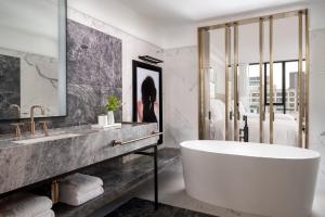 a bath room with a tub, mirror and a painting on the wall at Four Seasons Hotel Montreal in Montreal