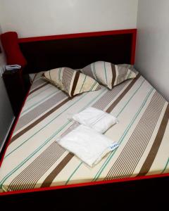 a bed with a red headboard with two towels on it at HOTEL KISS - TABOÃO DA SERRA in Taboão da Serra
