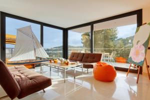 a living room with a table and a sailboat in the window at Naranja in Tamariu