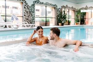 a man and a woman in a swimming pool at Marmot Lodge Jasper in Jasper
