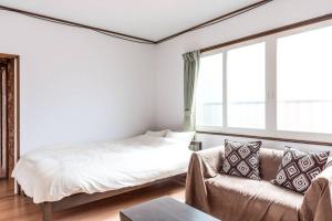 - une chambre blanche avec un lit et un canapé dans l'établissement Hakodate House, à Hakodate