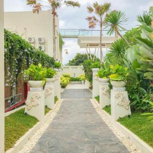 a garden path with potted plants in a building at Luminor Hotel Banyuwangi By WH in Banyuwangi