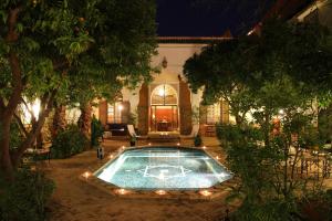a swimming pool in the yard of a house at night at Riad Laila in Marrakech