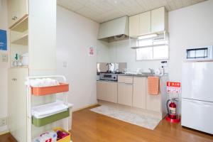 a kitchen with white cabinets and a refrigerator at Enoshima Apartment Hotel in Fujisawa
