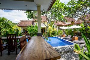 an outdoor patio with a wooden table and a swimming pool at Sisin Ubud View in Ubud