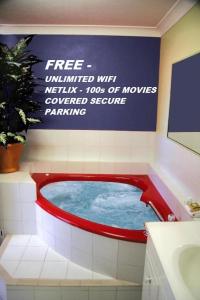 een hot tub in een badkamer met een bord bij Avlon Gardens Motel in Ballina
