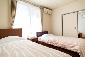 Ліжко або ліжка в номері Enoshima Apartment Hotel