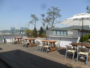 una terraza con mesas, sillas y sombrilla en Urban Boutique Hotel, en Anyang