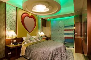 Zheng Yi Classic Hotel & Motel في مدينة تايتونج: غرفة نوم مع سرير وبقلب على الحائط