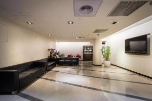 a lobby with black furniture and a flat screen tv at New World Hotel in Taipei