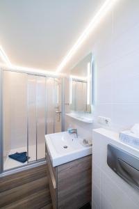 a white bathroom with a shower and a sink at Deichhotel Grube in Dorum Neufeld