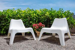 two white chairs sitting next to a plant at Cornisa Apartments in Patalavaca
