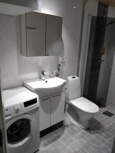 uma casa de banho com um WC, um lavatório e uma máquina de lavar roupa em Siljonportti Apartments em Rovaniemi
