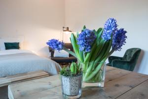 een vaas met blauwe bloemen op een houten tafel bij Hof Olmenstein in Goes