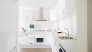 una cucina bianca con armadi bianchi e lavandino di Cornisa Apartments a Patalavaca
