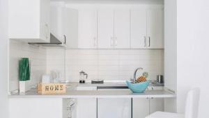 a kitchen with white cabinets and a bowl of fruit on the counter at Cornisa Apartments in Patalavaca