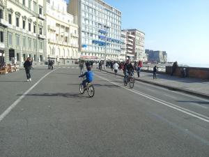 a group of people riding bikes down a city street at Napoli Sea in Naples