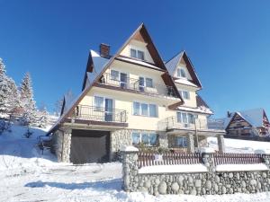 una casa grande en la nieve con una valla en 9 Sił Murowany Dom, en Bukowina Tatrzańska