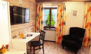 ein Wohnzimmer mit einem Schreibtisch, einem Stuhl und einem TV in der Unterkunft Pension Kranzmayr in Sankt Wolfgang