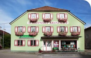 un edificio verde con persiane rosse e fiori sopra di Pension Kranzmayr a Sankt Wolfgang