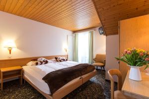 Schlafzimmer mit einem Bett, einem Tisch und einem Fenster in der Unterkunft Hotel Oberland in Lauterbrunnen