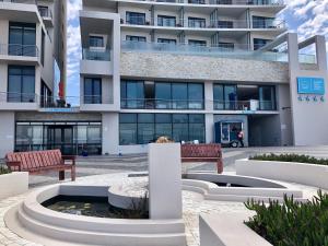an apartment building with a fountain in front of it at Blaauwberg Beach Hotel in Bloubergstrand