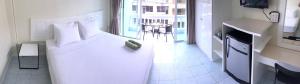 a bedroom with a white bed and a balcony at Thai Orchid Guest House in Jomtien Beach