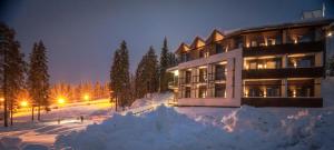 un gran edificio en la nieve por la noche en Hotel Aateli Hillside en Vuokatti
