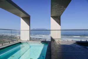 a swimming pool with a view of the ocean at Blaauwberg Beach Hotel in Bloubergstrand