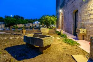 un banc en pierre assis à l'extérieur d'un bâtiment dans l'établissement Residenza Storica PARCO LANOCE, à Poggiardo