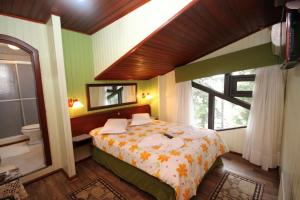 1 dormitorio con cama, espejo y ventana en Pousada casa da Colina, en Gramado