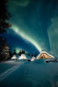 un grupo de tiendas en la nieve con un arco iris en el cielo en Wilderness Hotel Muotka & Igloos, en Saariselkä