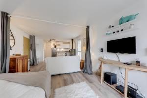 sala de estar blanca con TV y sofá en Le Rivage, en Arzon