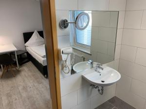 a bathroom with a sink and a mirror and a bed at Casino Hotel Neubeckum in Neubeckum