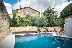 a swimming pool with chairs and a house at Le Castellas Hotel & SPA - PONT DU GARD - UZES in Collias