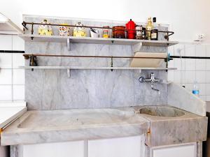 a kitchen with a sink and shelves on the wall at Villino a 20 metri dal mare in Levanto