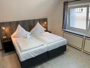 1 dormitorio con 1 cama con sábanas blancas y ventana en Casino Hotel Neubeckum, en Neubeckum