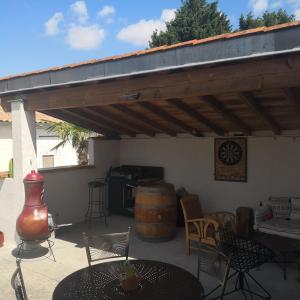 eine Terrasse mit Markise, Tischen, Stühlen und einem Fass in der Unterkunft La Clé du Puy in Cabariot