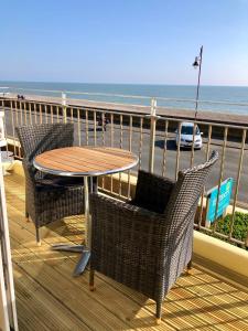een tafel en stoelen op een balkon met uitzicht op het strand bij Mariners Hotel in Seaton