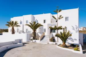 a white building with palm trees in front of it at Nikos Hotel in Karterados