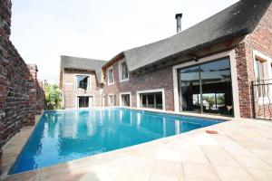 una piscina frente a un edificio de ladrillo en 19th Hole Golf Villa Guesthouse, en Worcester