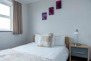a bedroom with a bed with white sheets and a window at Marine Court in Bundoran