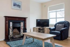 a living room with a fireplace and a chair and a table at Marine View -3 Bedroom Townhouse in Bundoran
