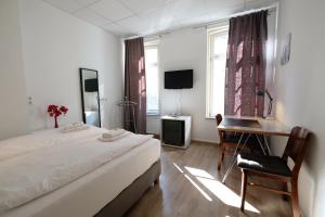 a bedroom with a bed, chair, desk and a television at Elisabeth Apartments in Marburg an der Lahn