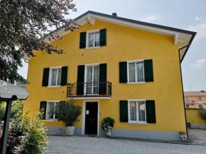 a yellow house with black shutters at La Meridiana Affittacamere in Colorno