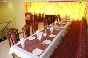 a long table with white tables and chairs in a room at Saiesh International Hotel in Mapusa